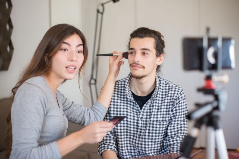 Stylistka wykonuje makijaż mężczyźnie podczas lekcji stylizacji